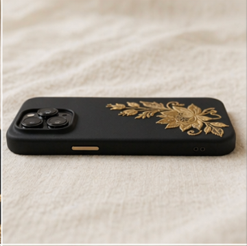 Black phone case with gold floral design on a white fabric background