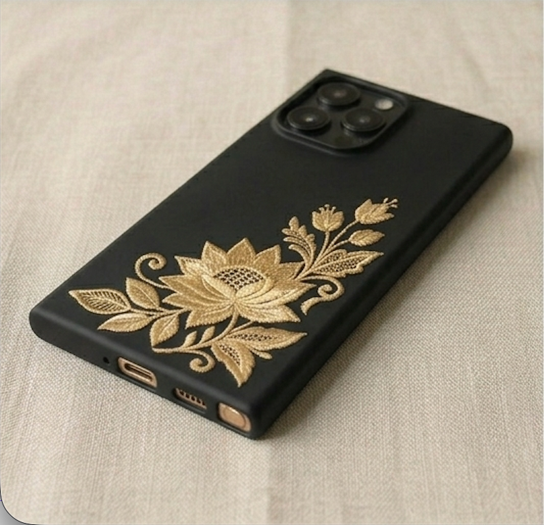 Black phone case with gold floral design on a beige fabric background