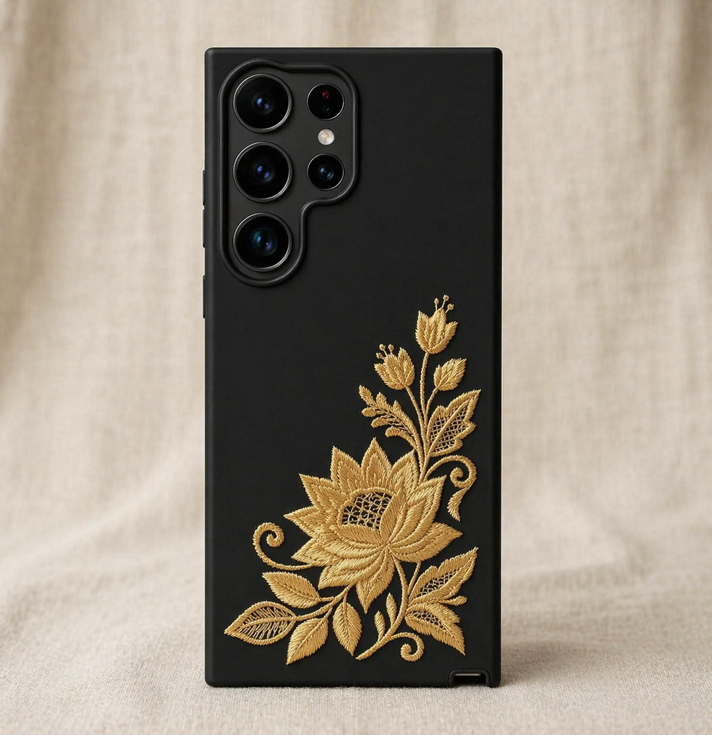Black phone case with gold floral design on a beige fabric background