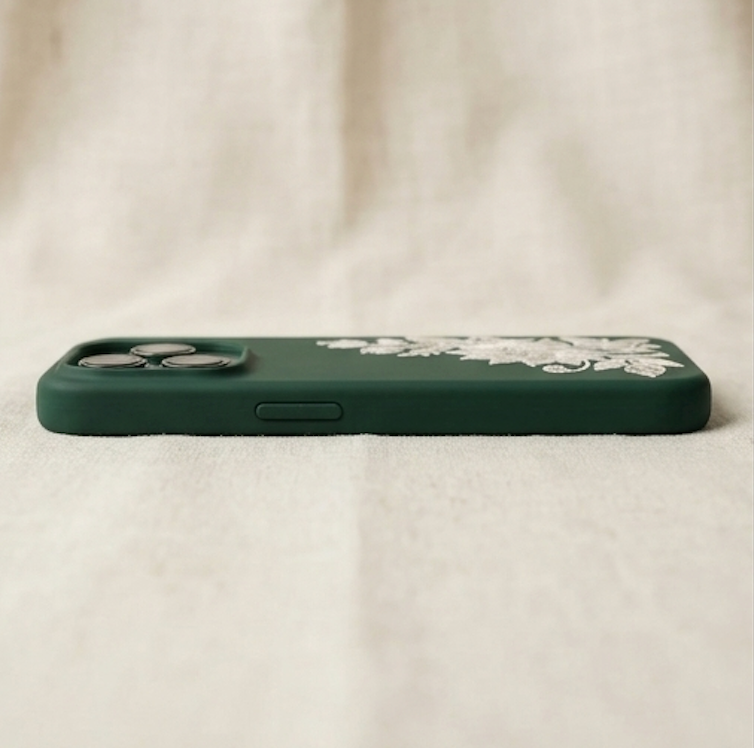 Green phone case with floral design on a beige fabric background