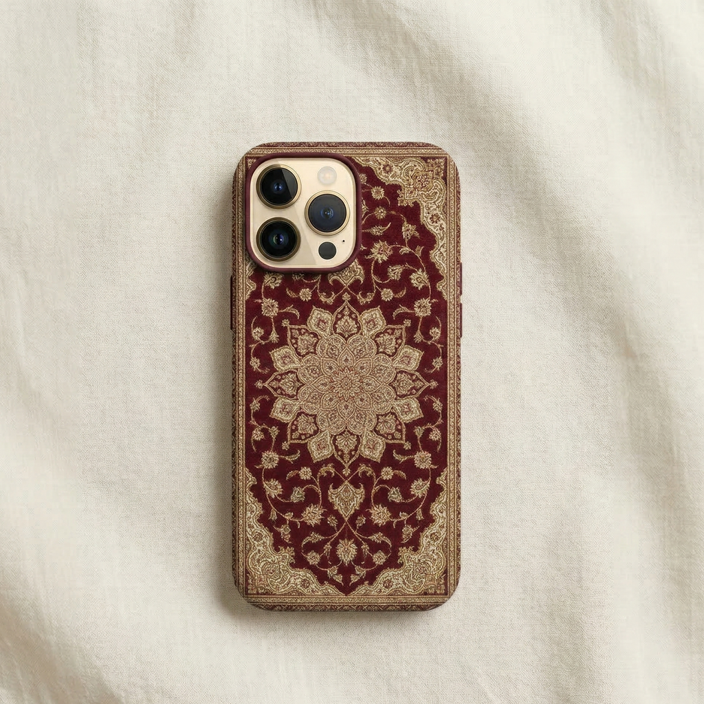 iPhone case inspired by traditional South Asian carpet design, rich deep maroon background featuring an elegant Persian-Mughal style carpet motif with intricate floral medallion in the center and subtle ornamental borders, detailed woven texture inspired by Pakistani and Mughal rugs, refined pattern with gold, ivory, and muted red accents, symmetrical composition, sophisticated cultural aesthetic, photographed as high-end product photography with natural studio lighting on cream backrgound