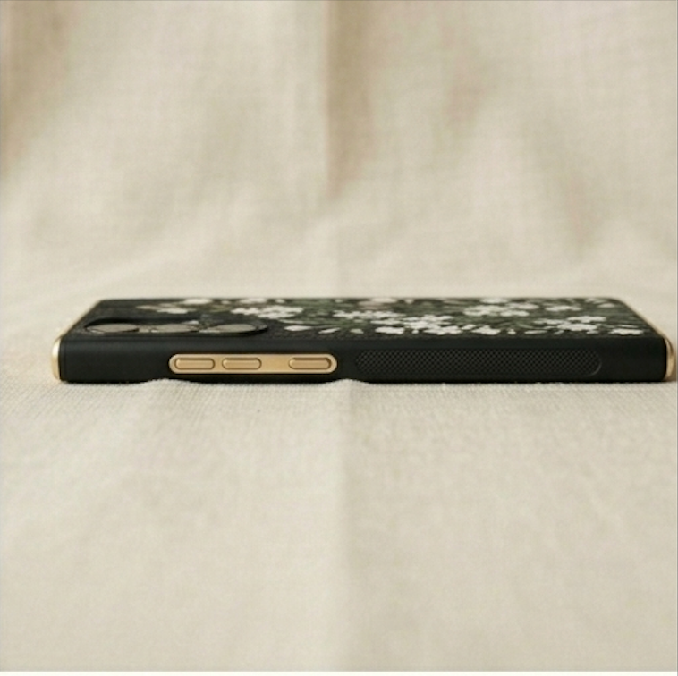 Black phone case with floral design on a beige fabric background