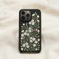 Luxury iphone case with matte black background featuring a dense vertical garden of delicate jasmine flowers (motiya / chameli), small white jasmine blossoms with soft yellow centers growing on tall slender green stems, mixed with buds and leaves, illustrated in a hand-painted botanical style inspired by South Asian floral art and Mughal garden aesthetics, elegant composition with flowers rising upward across the case, vibrant but refined colors, modern luxury aesthetic